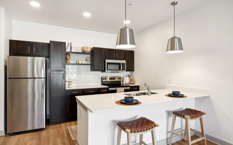 Apartment kitchen with pendant lights and whit countertops