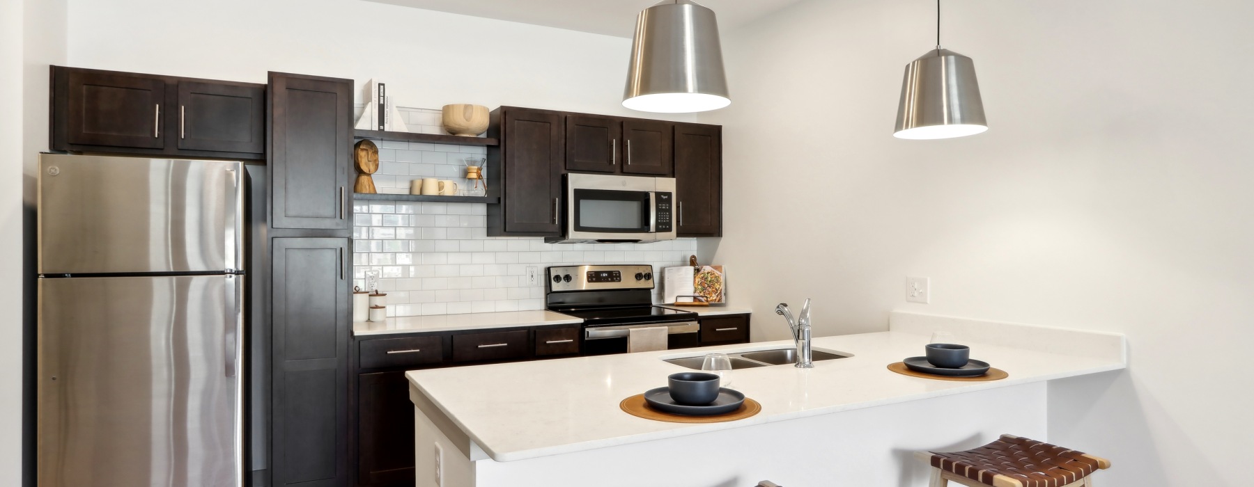 Apartment kitchen with pendant lights and whit countertops