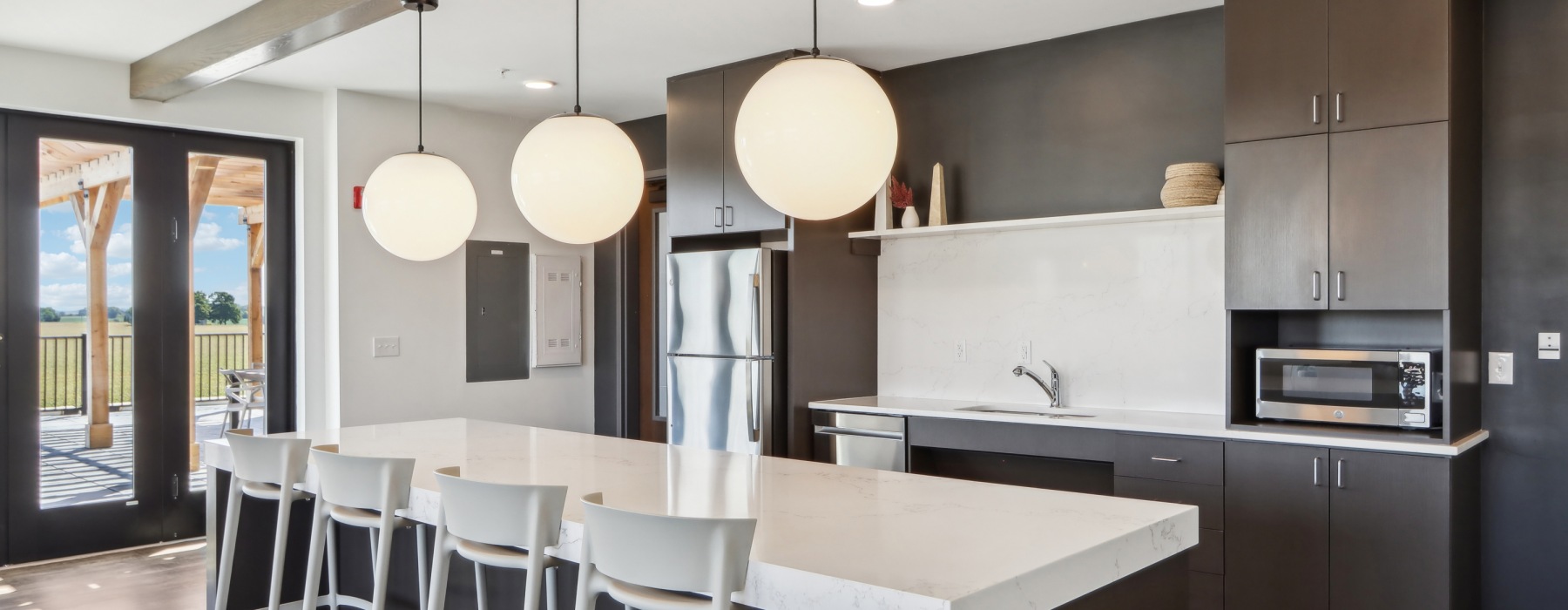 Lounge kitchen with white countertops and bar stools at the island